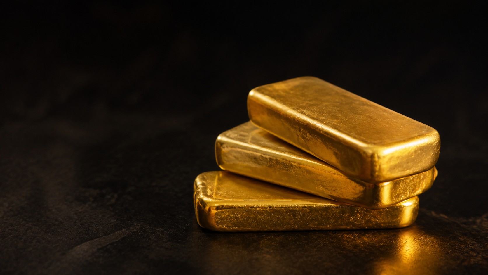 A stack of gold bullion bars on a dark surface, representing physical gold you actually own