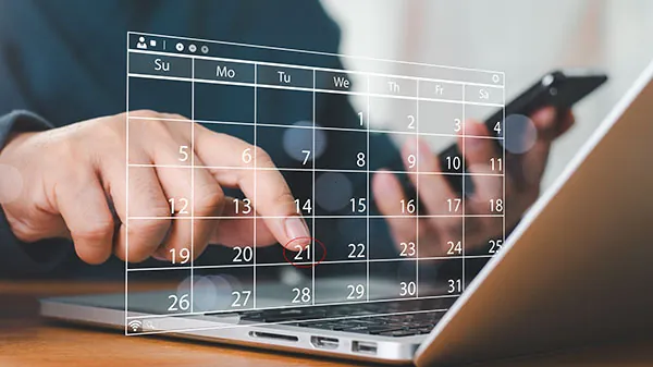 Hand scheduling recurring gold and silver purchases on a laptop calendar