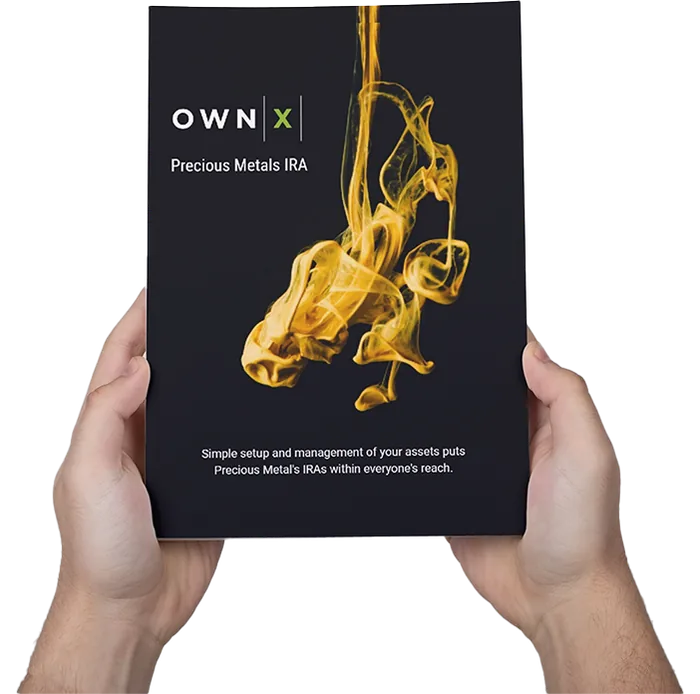 Two hands holding the printed OWNx Precious Metals IRA guide, a black booklet with a swirl of gold on the cover